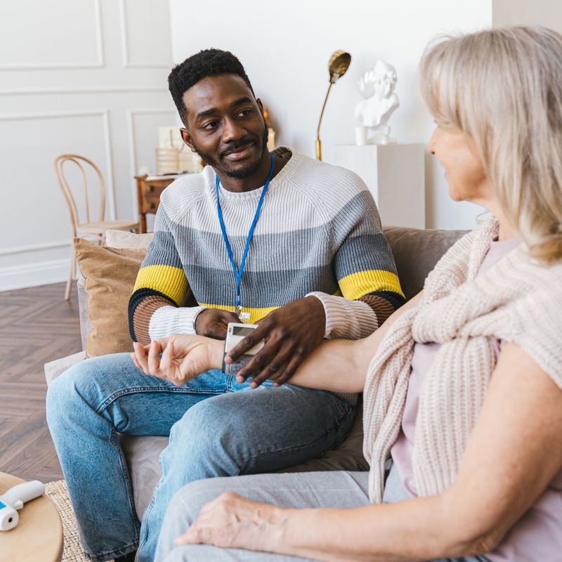 A support worker sitting and talking with an older woman in her living room